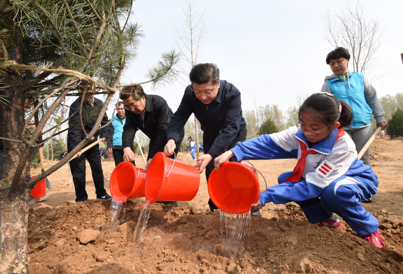 这是习近平同大家一起给刚栽下的树苗浇水。新华社记者 李学仁 摄